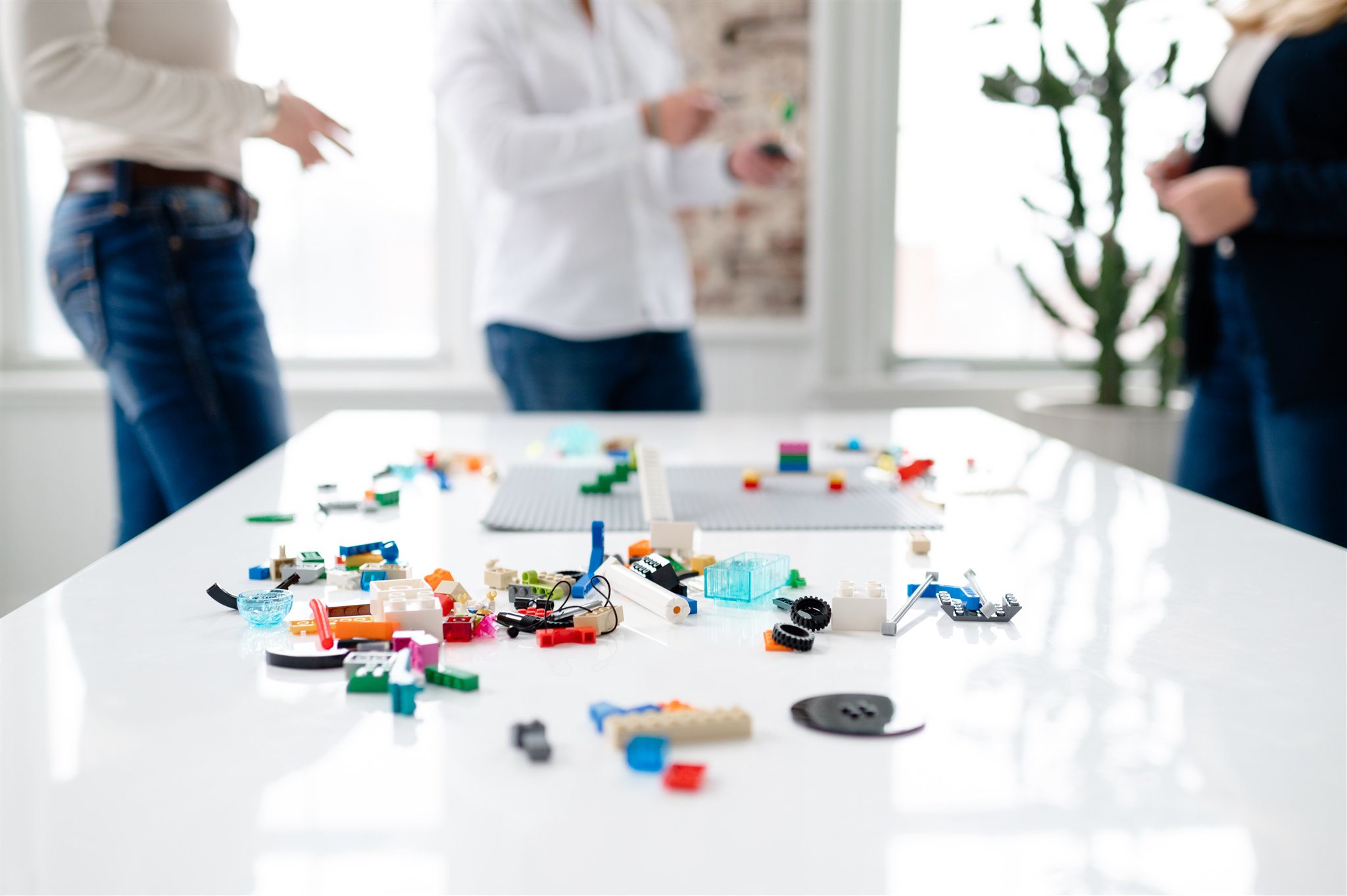 Legos on a white table with people standing in the background